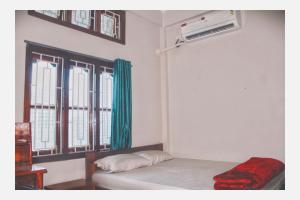 a room with a bed and a window with green curtains at Mini Emphum 2BHK Apartment in Namsai