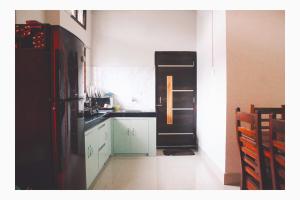 a kitchen with a black refrigerator and white cabinets at Mini Emphum 2BHK Apartment in Namsai +7 photos