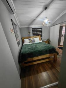 a bedroom with a bed with a green comforter at The Hideaway Cabin in Pretoria
