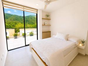 a white bedroom with a bed and a large window at Miramonte Payande in Nimaima