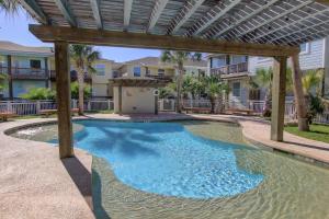 a swimming pool with a pergola in front of a house at Baja Breeze in Port Aransas