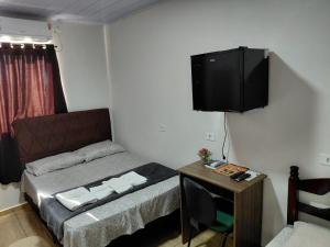 a small bedroom with a bed and a television on the wall at Kurten Hotelaria in Cândido de Abreu
