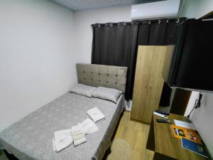 a small bedroom with a bed and a flat screen tv at Kurten Hotelaria in Cândido de Abreu