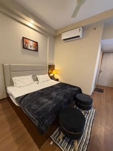 a bedroom with a bed and two stools in it at Av stays in Greater Noida