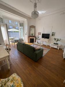 a living room with a green couch and a television at La belle époque ardennaise in Sedan