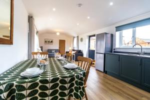 a kitchen and dining room with a table with a green and white table cloth at The Stables in Sibbertoft +5 photos