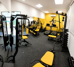 a gym with several treadying machines and yellow chairs at Atlântico Golden Apart Hotel in Santos