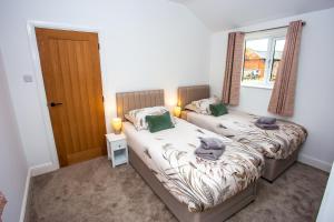 two beds in a small room with a window at The Stables in Sibbertoft