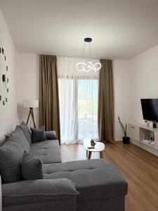 a living room with a gray couch and a tv at Foel Apartament in Tirana