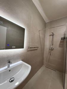 a bathroom with a sink and a shower with a mirror at Foel Apartament in Tirana +16 photos