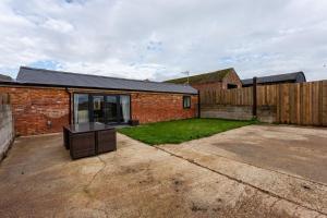 a brick house with a fence and a yard at The Stables in Sibbertoft