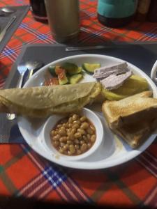 a plate of food with a sandwich and beans at Posho Sunset Mara in Sekenani