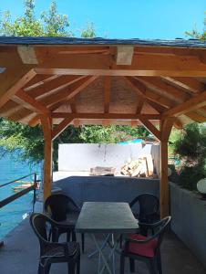 a picnic table and chairs under a wooden pergola at Mostar kuca pored jezera in Mostar