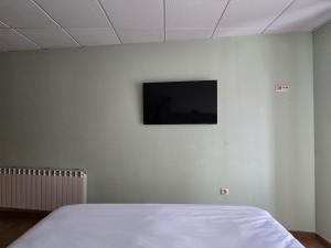 a bedroom with a flat screen tv on a wall at Hostal La Cigüeña in El Espinar +38 photos