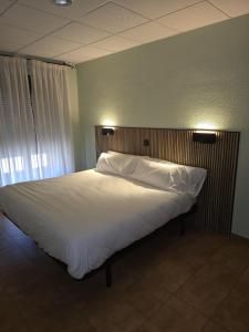 a large bed in a bedroom with lights on it at Hostal La Cigüeña in El Espinar