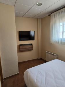 a bedroom with a bed and a television on the wall at Hostal La Cigüeña in El Espinar