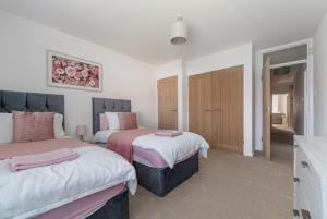 a bedroom with two beds with pink and white sheets at Fairways - Flat 3 in Weston-super-Mare