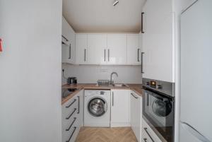 a kitchen with white cabinets and a washer and dryer at Fairways - Flat 3 in Weston-super-Mare