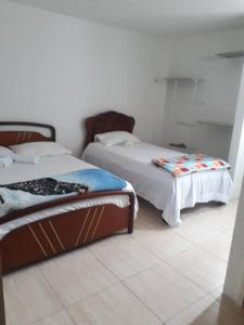 two beds sitting in a room with a tiled floor at Vilma's BnB in Mérida