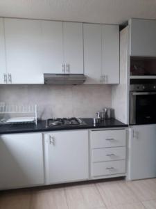 a kitchen with white cabinets and a black counter top at Vilma's BnB in Mérida