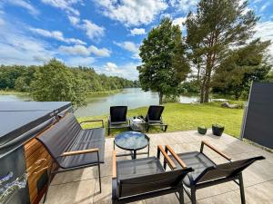 a patio with chairs and a view of a river at Black Cat House Radailiai in Radailiai