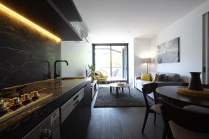 a kitchen with a sink and a living room at Turnkey Accommodation-North Melbourne in Melbourne