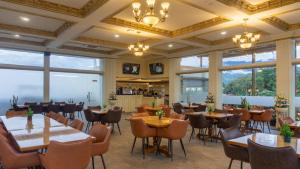 a restaurant with tables and chairs and large windows at Atiyan Hotel Syariah in Bukittinggi