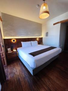 a bedroom with a large white bed and a lamp at El Balcón in Cusco
