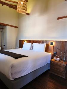 a bedroom with a large white bed with a wooden headboard at El Balcón in Cusco