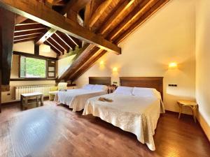 two beds in a room with wooden ceilings at Hotel Rural El Fundil in El Pino