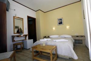 a bedroom with a white bed and a table at Poseidon Hotel in Ios Chora +36 photos
