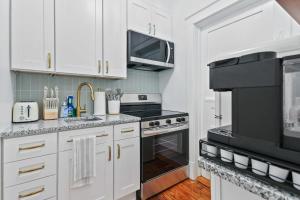 a kitchen with white cabinets and black appliances at Darling Downtown Renovated Historic Condo Walkable in Savannah
