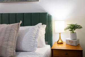 a bed with a green headboard and a table with a lamp at Darling Downtown Renovated Historic Condo Walkable in Savannah