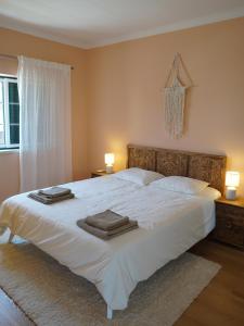 a bedroom with a large white bed with towels on it at Capsule Marisol Family Retreat in Corroios