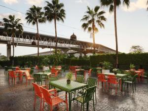 a group of tables and chairs with palm trees and a bridge at ibis Bangkok IMPACT in Nonthaburi