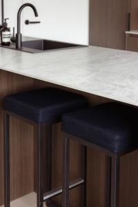 a kitchen with two black stools under a counter at Sunny duplex penthouse, close to beach, parking in Knokke-Heist +30 photos