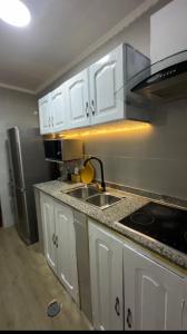 a kitchen with white cabinets and a sink and a refrigerator at Cintya Maria in Camama