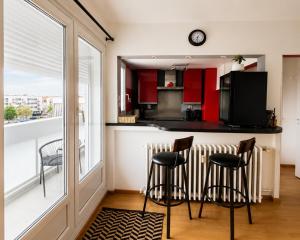 a kitchen with red cabinets and a counter with stools at La parenthèse in Calais
