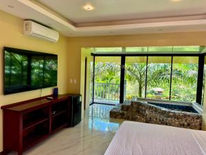 a bedroom with a tub and a bed and a television at Hosteria Arizona in Puyo
