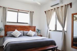 a bedroom with a bed and two windows at Casa Velamar in Isla Mujeres