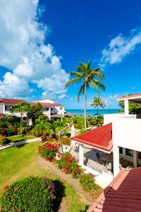 a view of a house with a palm tree and flowers at Antigua Village Beach Resort in Saint Johnʼs