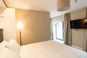 a bedroom with a white bed with a lamp and a window at Westport Selfcatering Suites in Westport
