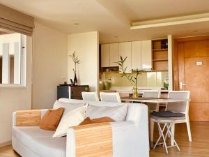 a living room with a white couch and a kitchen at Le Grand Bleu in Koh Samui