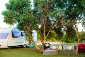a white caravan parked next to a tree with a couch at The Place in Albufeira