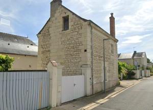 an old brick building with a white fence at Centre Bourg d'Avoine Cottage in Avoine