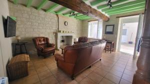 a living room with leather furniture and a fireplace at Centre Bourg d'Avoine Cottage in Avoine