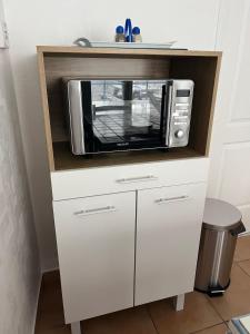 a microwave oven sitting on top of a white cabinet at Centre Bourg d'Avoine Cottage in Avoine