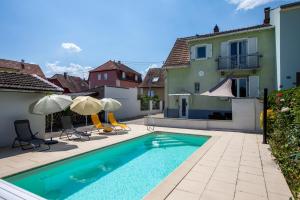 a swimming pool with umbrellas and a house at -New- Colmar, Parking, Comfort, Spacious in Ingersheim