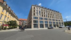 a person riding a bike in front of a building at AlegraStay Apartments - Dresden City in Dresden