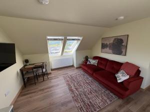 a living room with a red couch and a table at Coorie-Tigh in Connel
